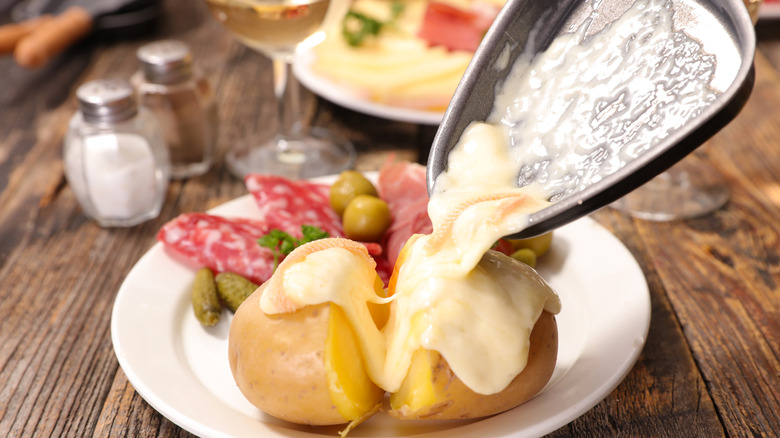 scoop pouring raclette over potato