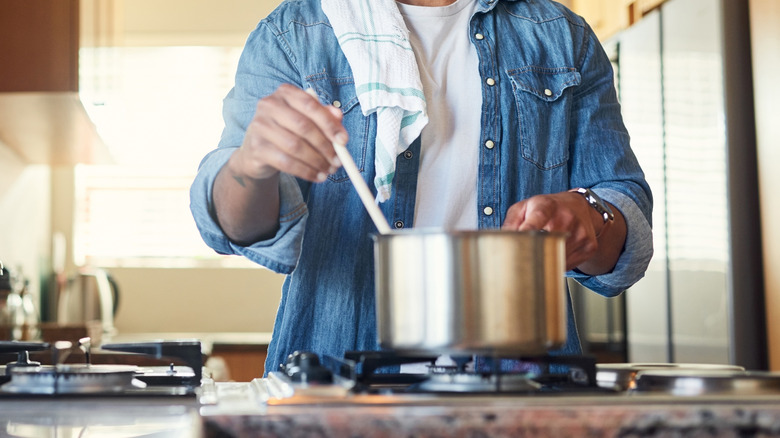 A person stirs a pot on the stove