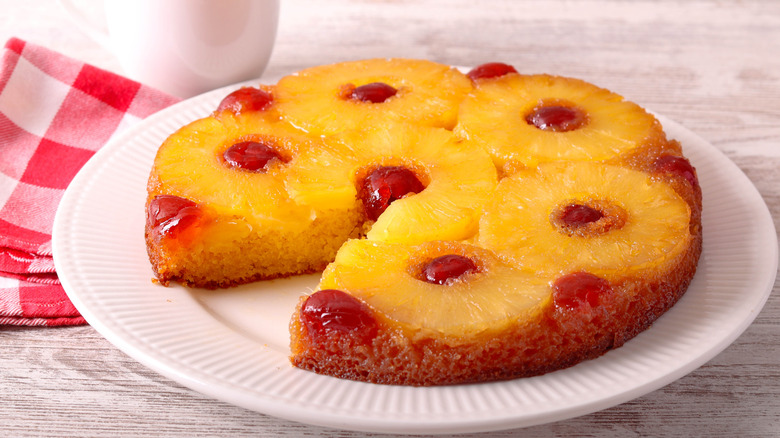 A pineapple upside down cake with a single piece taken out of it