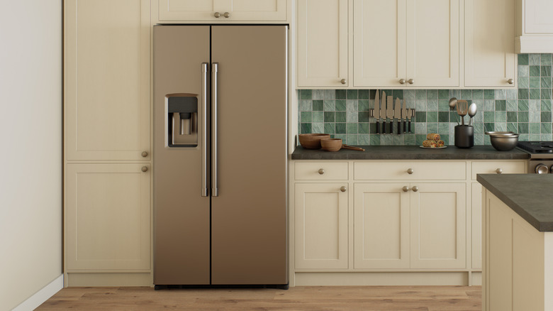 A double door refrigerator sits in a green and white kitchen