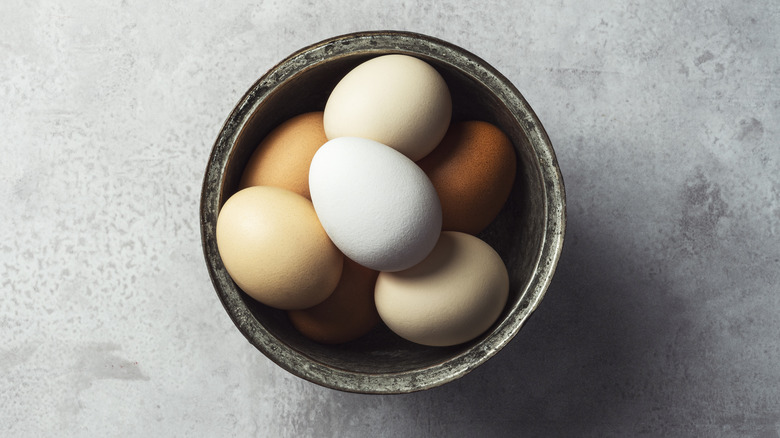 A bowl of multicolored eggs on a counter top