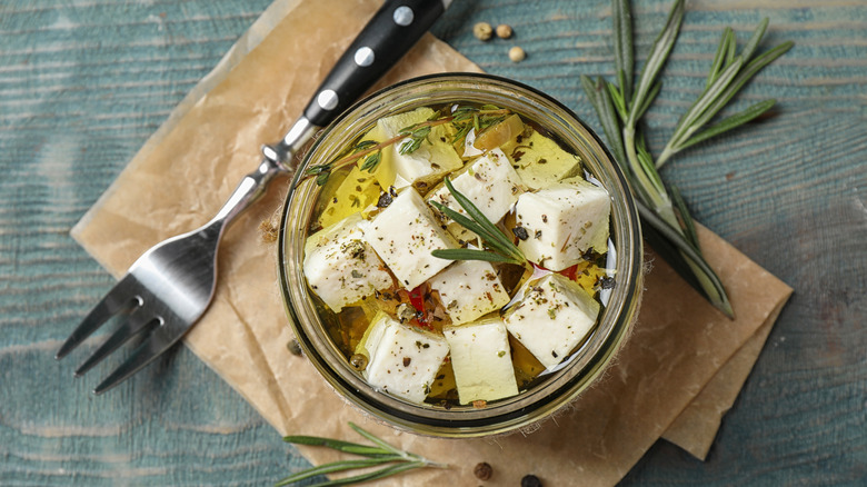 Jar of marinated cheese with herbs