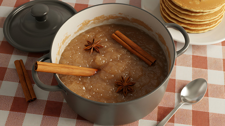 Apple butter with star anise in it on a checkered table clothe next to pancakes
