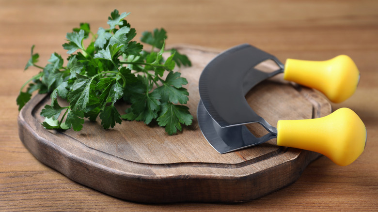 Mezzaluna on a cutting board with herbs