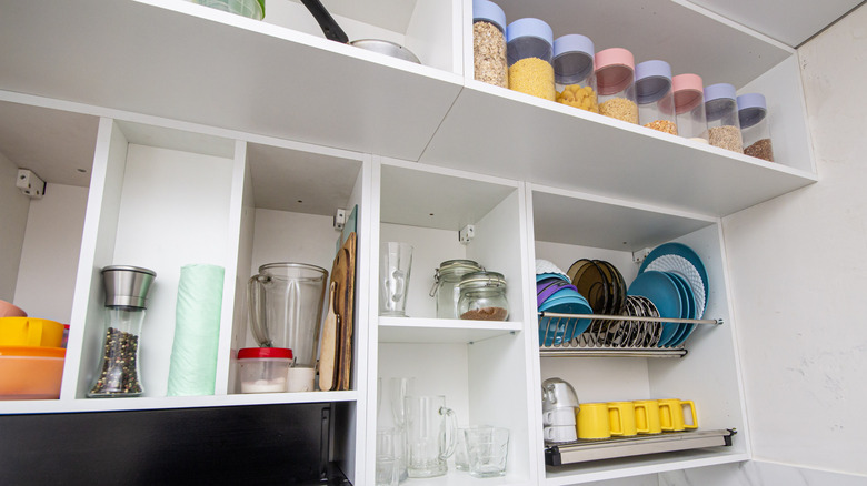 Open modular shelving in a contemporary kitchen, with cups, plates, and food on display