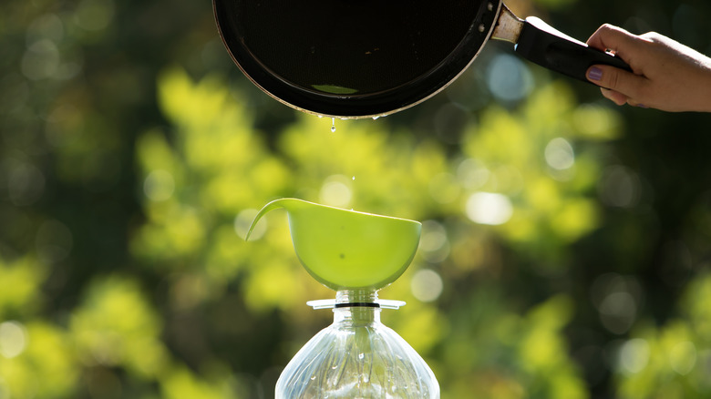 Used cooking dripping into a funneled bottle for disposal