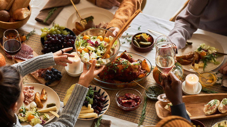 Woman passing salad at dinner party