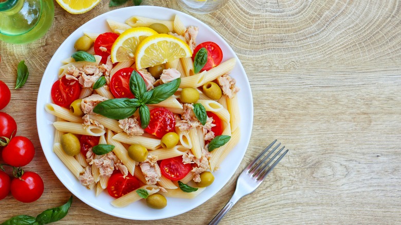 cold pasta with lemon olives tomato on wooden table