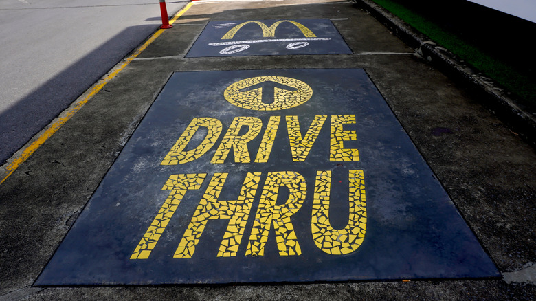 "Drive Thru" with arrow and golden arches painted in the ground at a McDonald's