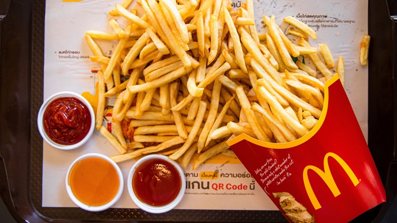 A carton of McDonald's fries and 3 sauces on a serving tray