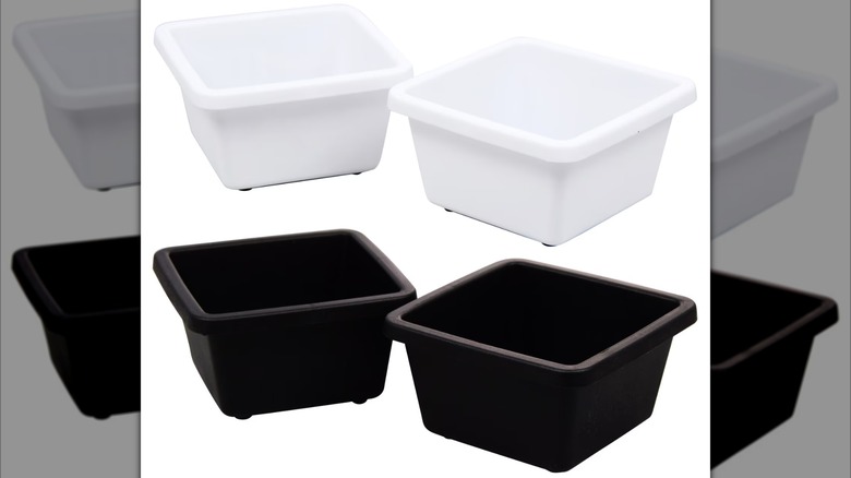 Two pairs of small, square, plastic drawer organizers, one in black and one in white
