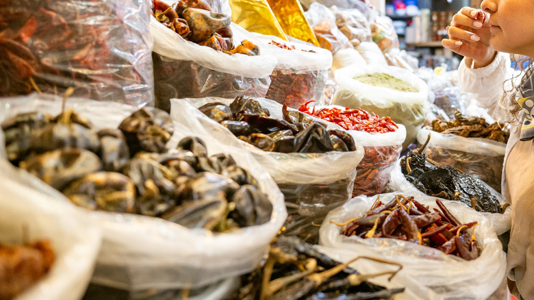 A young woman shopping bins of dried herbs and spices