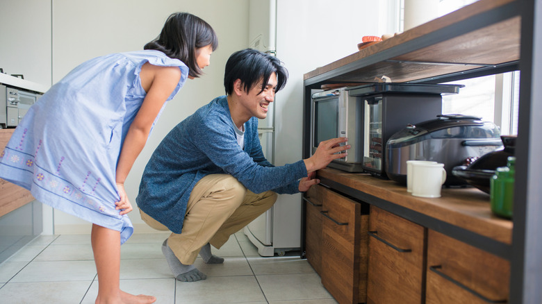 Father and daughter using microwave