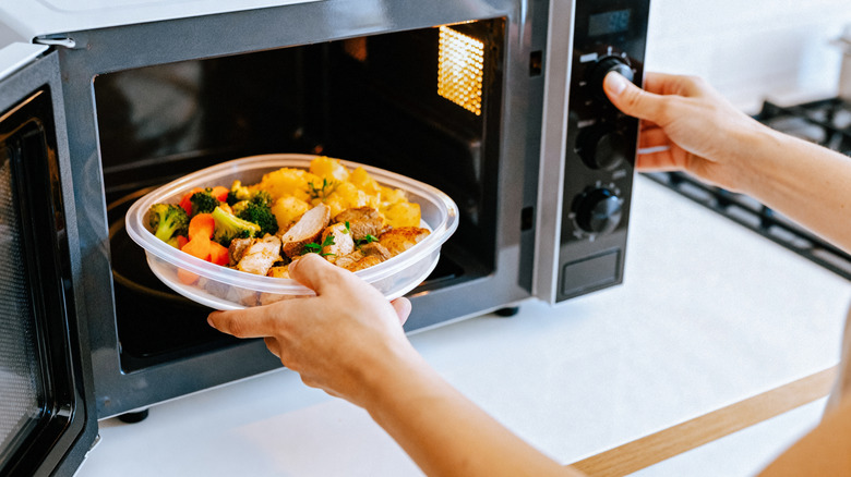 Person putting food in microwave