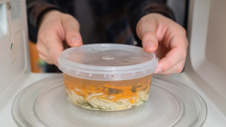 Person heating plastic container in microwave