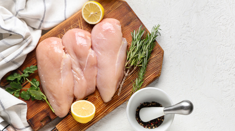 raw chicken breasts on cutting board with other ingredients