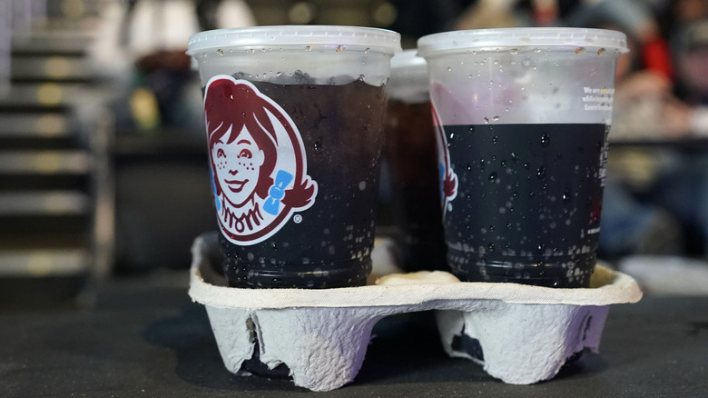 Four sodas in Wendy's drink cups, in a drink holder.