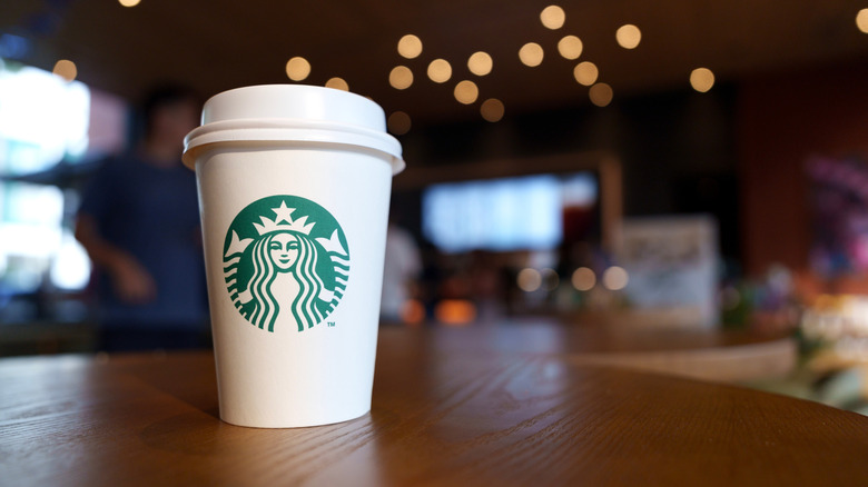 Starbucks takeaway coffee cup on a wooden cafe table