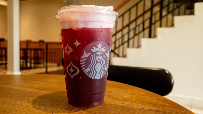 Red Starbucks berry drink in clear cup, on wooden table