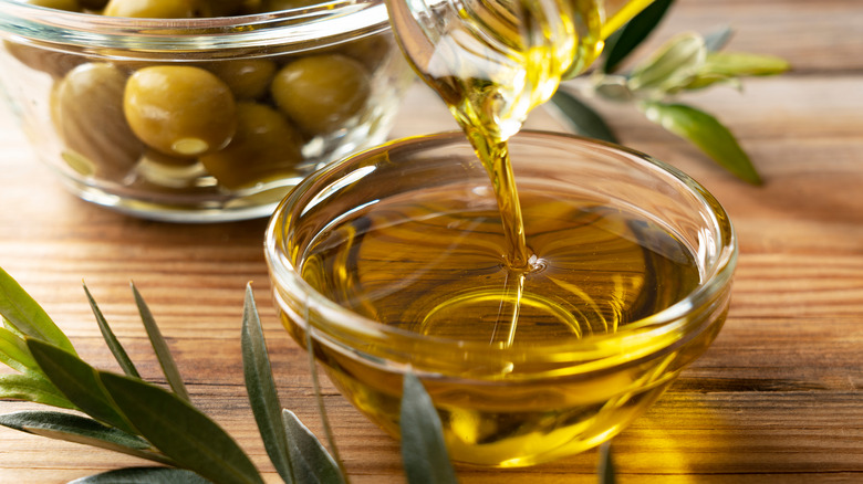 Olive oil being poured into a glass bowl