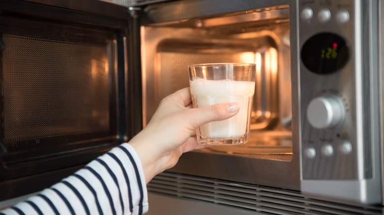 Woman warming a glass of milk in the microwave