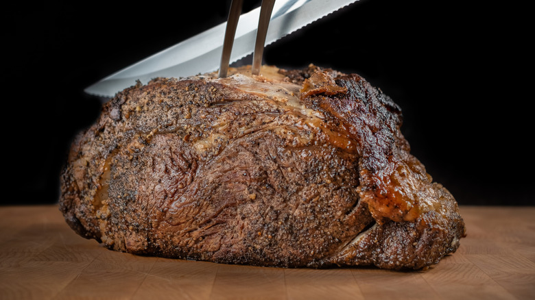 Prime rib end cut being sliced on a wooden surface
