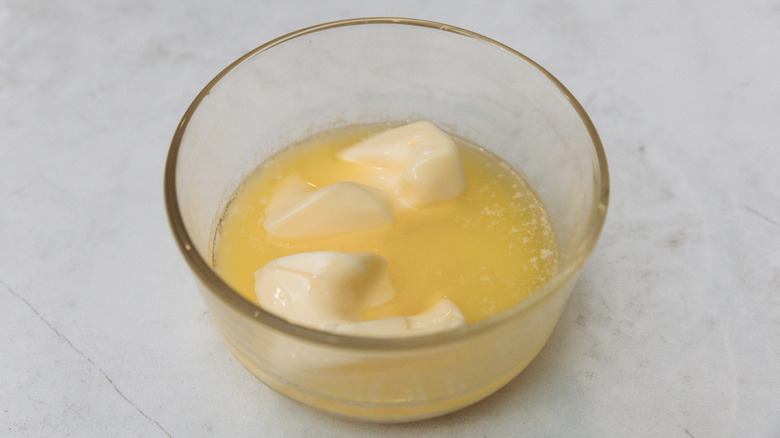 Butter almost melted in a glass dish against a white countertop