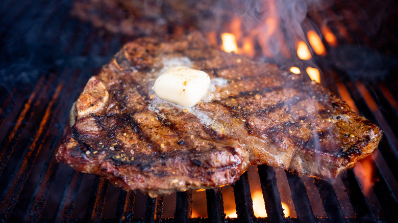 Porterhouse T-Bone topped with butter on a grill with flames