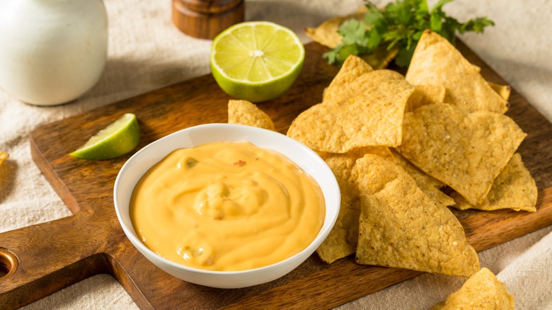 chips and queso dip on a cutting board