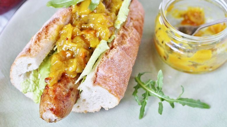 sausage in roll with greens and yellow chutney