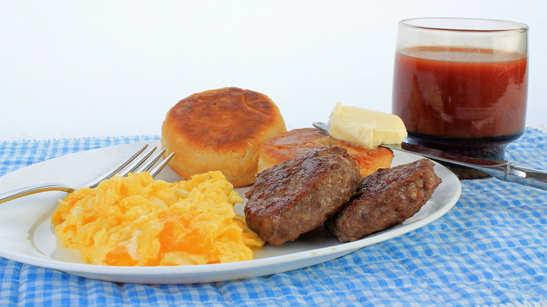 Scrambled eggs, sausage, and biscuits on a white plate