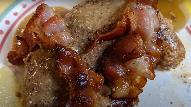 Close up of shad roe with bacon on a white plate