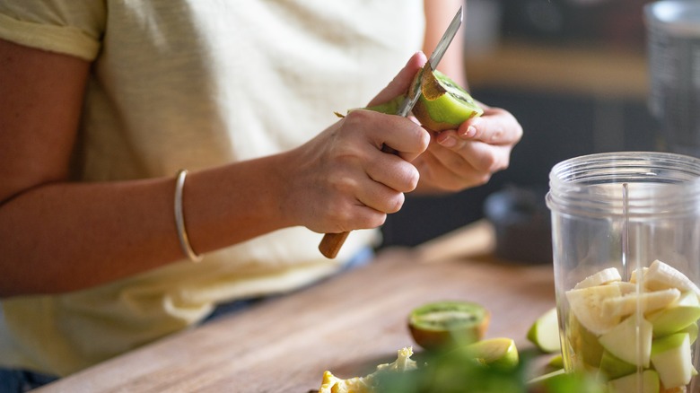 woman peeling kiwi with knife