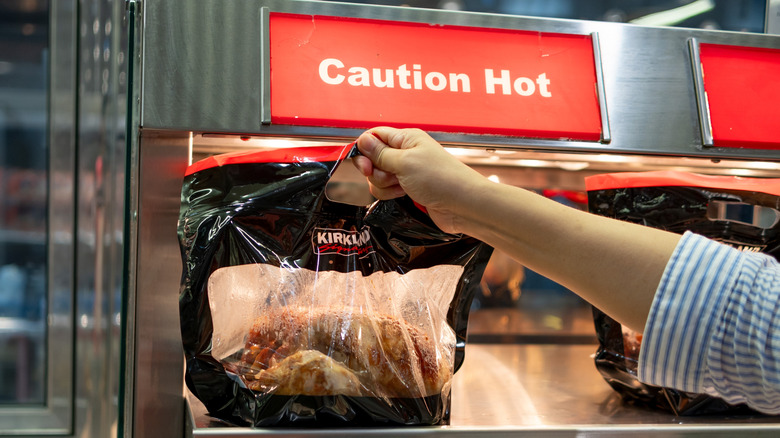 Hand grabbing Kirkland Signature rotisserie chicken