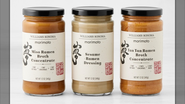 Two glass jars of medium-brown broth concentrate, and one glass jar of beige ramen dressing