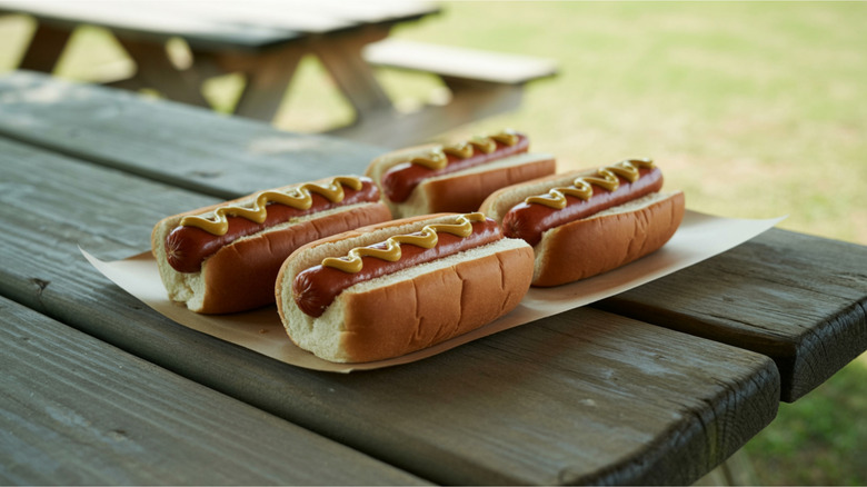 Hot dogs in buns on a picnic table