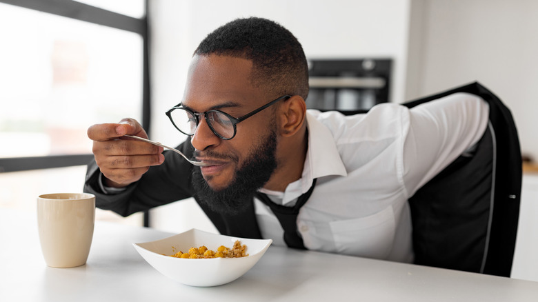 Man eating cereal putting on jacket