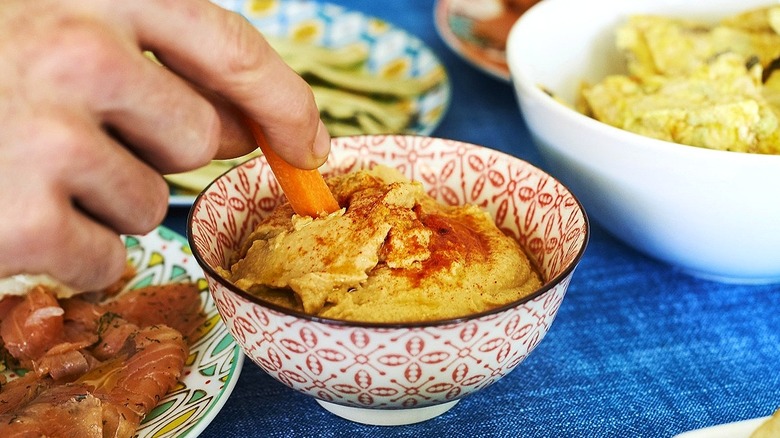 Hand dipping carrot in hummus