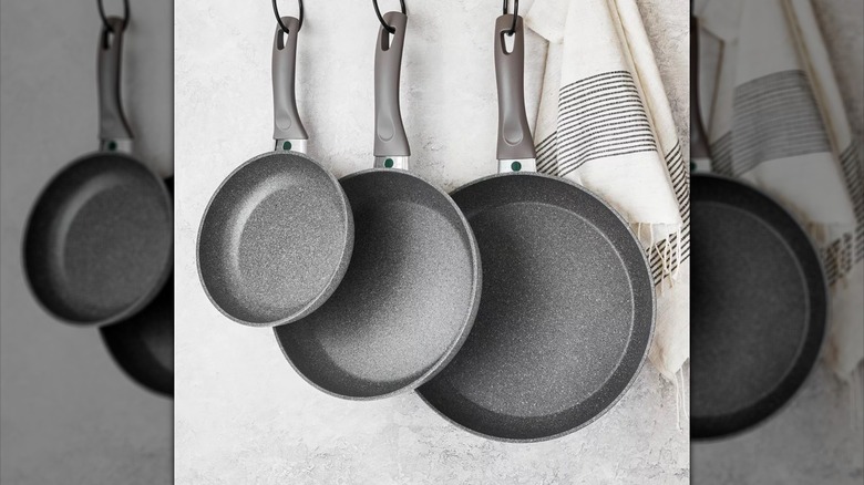 Three frying pans hanging from hooks in kitchen