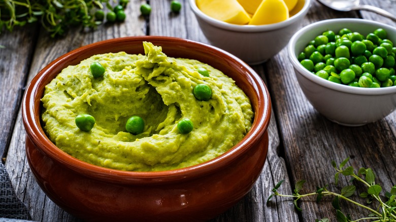 pea dip on table next to bowls of potato and peas