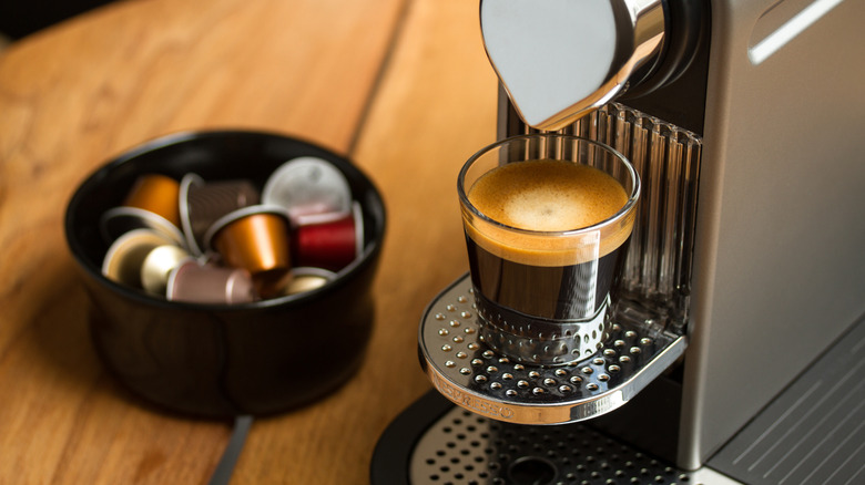 Coffee pods in a bowl next to a coffee machine and espresso