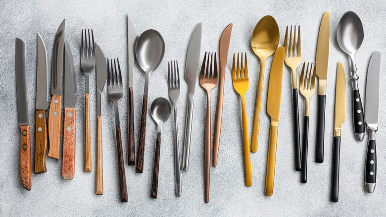 a row of various sizes of forks, spoons, and knives
