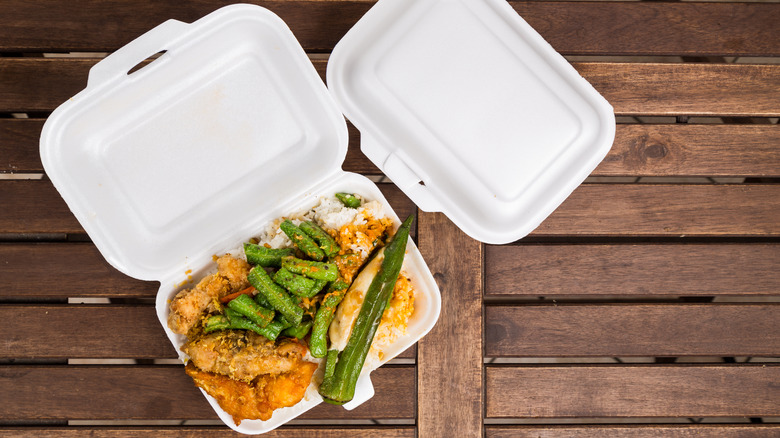 overhead view of a takeout meal with green veggies, rice, and fried meat in a Styrofoam container