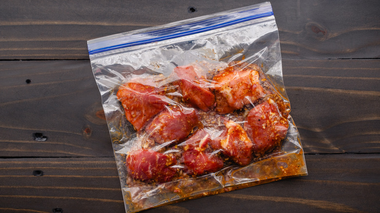 a zip-top bag full of chunks of pork with a marinade