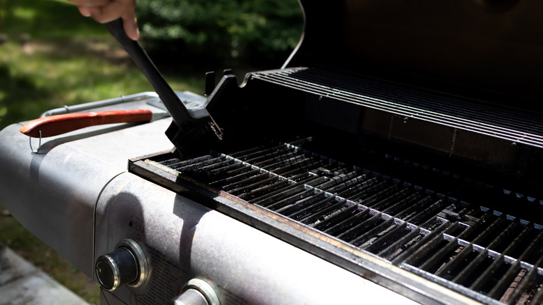 A person cleaning the grill in the backyard