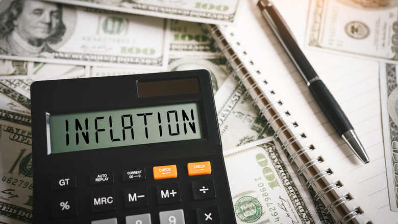 Calculator reading 'inflation' on $100 bills