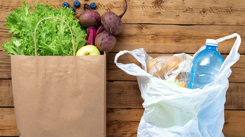 Paper and plastic grocery bags on rustic wooden background
