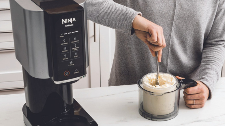 Hand stirring Ninja Creami pint on kitchen counter