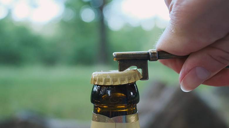 Hand holding a skeleton key opening a bottle