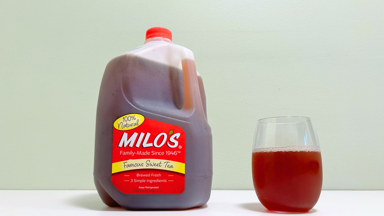 A gallon jug of Milo's famous sweet tea net to a mostly filled glass